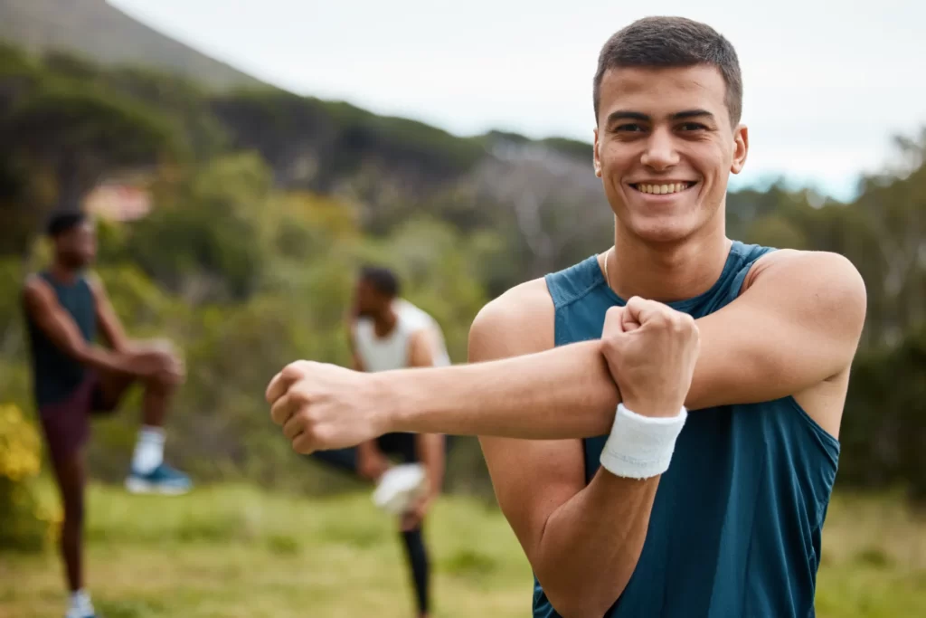 man stretching arms outdoors with friends utc